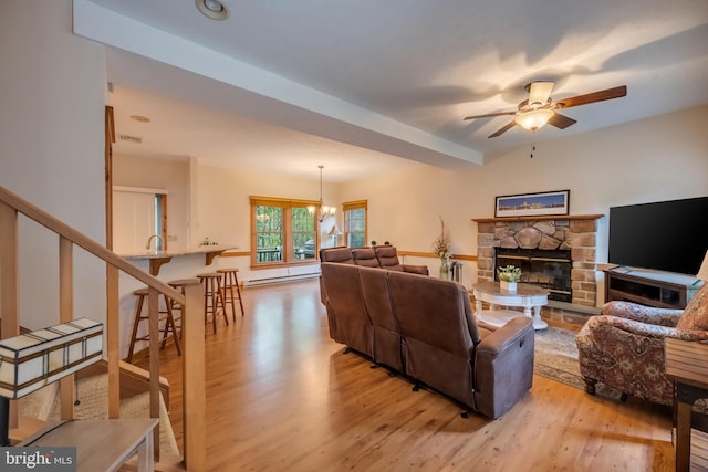 living room with ceiling fan with notable chandelier, sink, a baseboard radiator, light hardwood / wood-style flooring, and a fireplace