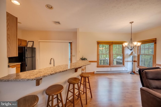 kitchen with pendant lighting, an inviting chandelier, black refrigerator, a baseboard radiator, and dark hardwood / wood-style flooring