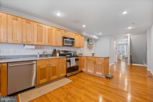 kitchen featuring light hardwood / wood-style flooring, stainless steel appliances, decorative backsplash, and sink