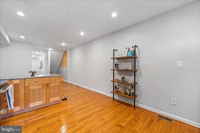 kitchen with stainless steel range and light hardwood / wood-style floors