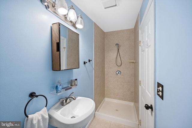 bathroom with tile patterned flooring, sink, and tiled shower