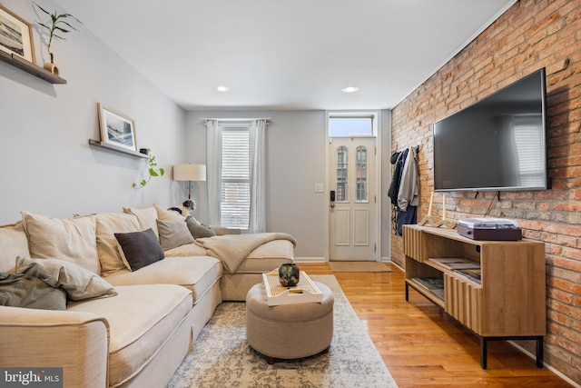 living room with light hardwood / wood-style floors and brick wall