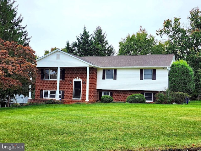 split foyer home with brick siding and a front lawn