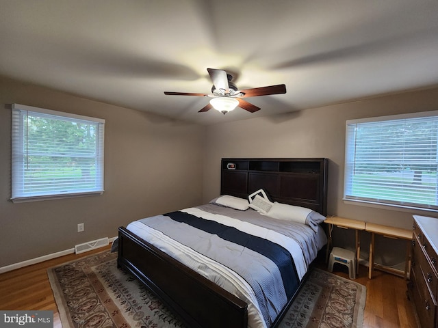 bedroom with ceiling fan, hardwood / wood-style floors, and multiple windows