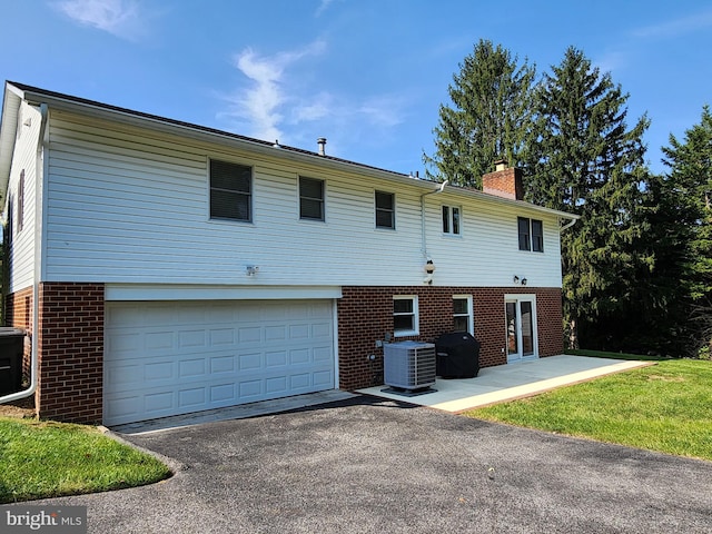 rear view of house featuring a garage and central AC