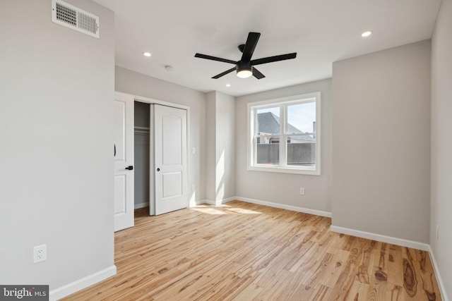 unfurnished bedroom with ceiling fan, light wood-type flooring, and a closet