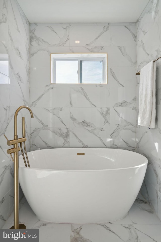 bathroom with tile walls and a tub