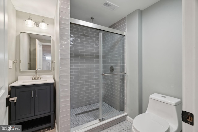 bathroom featuring tile patterned flooring, a shower with door, vanity, and toilet