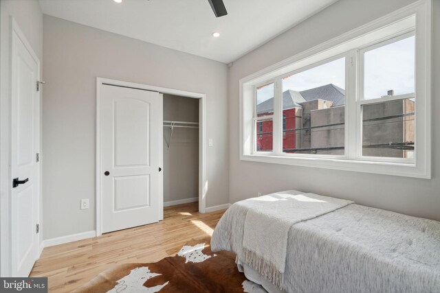 bedroom with ceiling fan, light hardwood / wood-style floors, and a closet