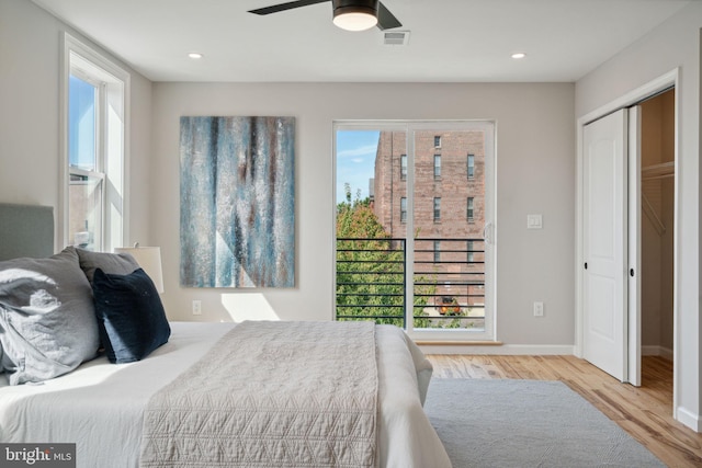 bedroom with a closet, light hardwood / wood-style flooring, multiple windows, and ceiling fan