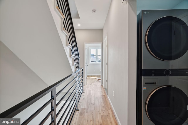 laundry room with light hardwood / wood-style flooring and stacked washer and clothes dryer