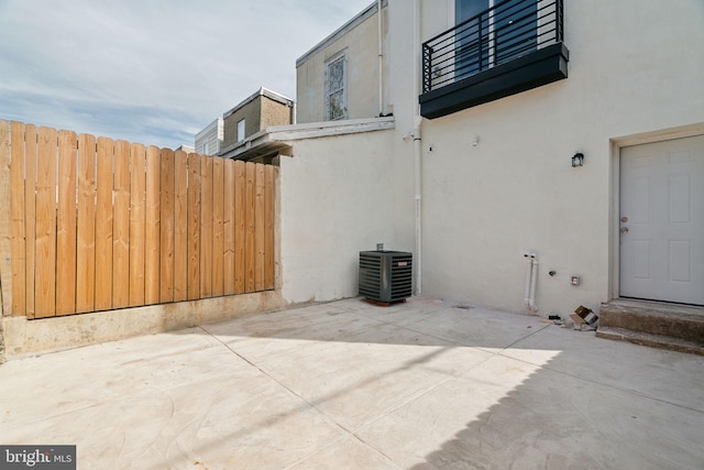 view of side of property with a balcony, a patio area, and central air condition unit