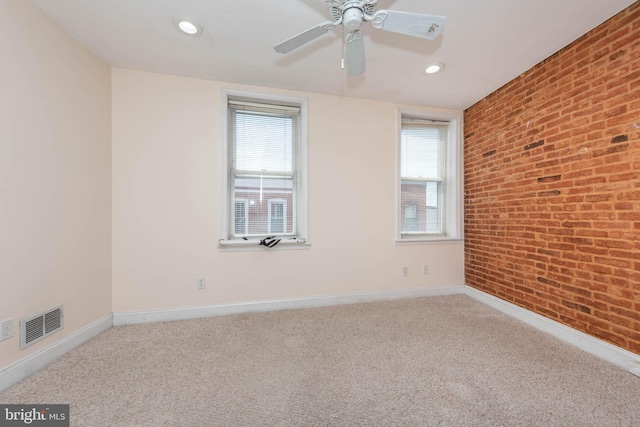 spare room featuring brick wall, carpet, and ceiling fan