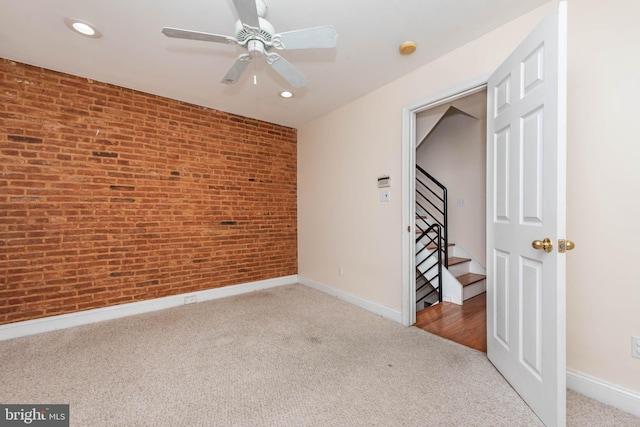 unfurnished bedroom with brick wall, carpet flooring, and ceiling fan