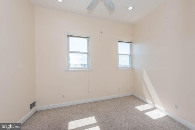 unfurnished room with ceiling fan, light colored carpet, and a wealth of natural light