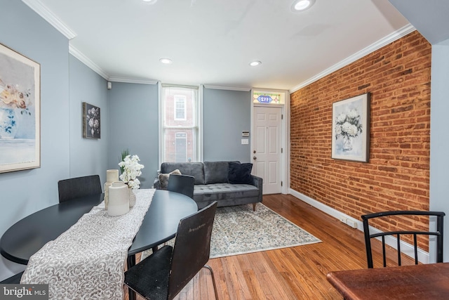 dining room featuring wood-type flooring, ornamental molding, and brick wall