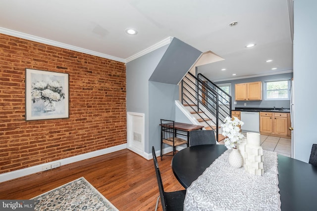 dining room with light wood-type flooring, crown molding, sink, and brick wall