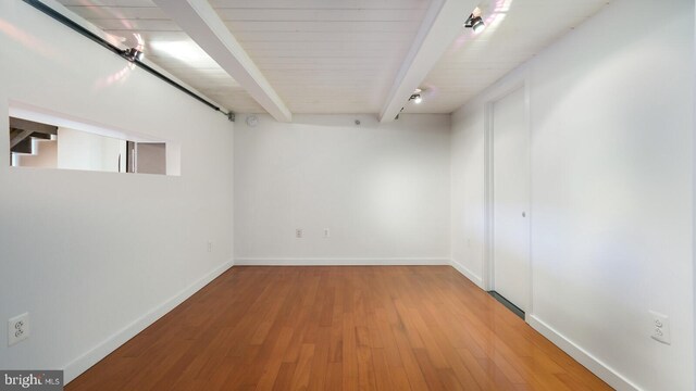 spare room with beamed ceiling and light hardwood / wood-style flooring