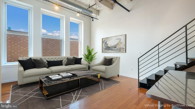 living room with wood-type flooring, beam ceiling, and a high ceiling