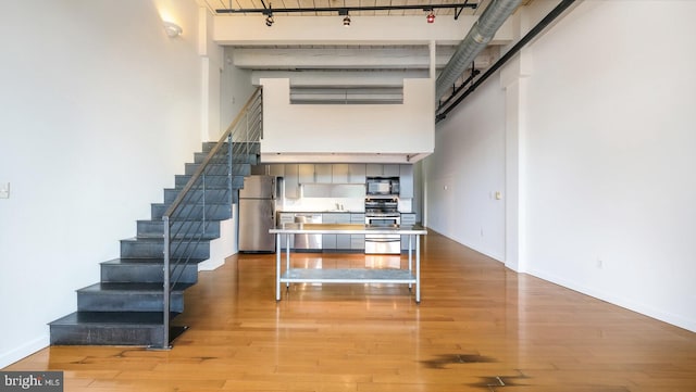 interior space featuring a towering ceiling, track lighting, hardwood / wood-style floors, and sink