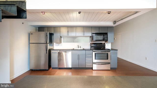 kitchen featuring appliances with stainless steel finishes, gray cabinetry, light wood-type flooring, wooden ceiling, and sink