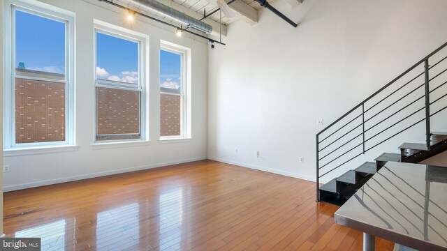 unfurnished living room featuring light wood-type flooring and a towering ceiling