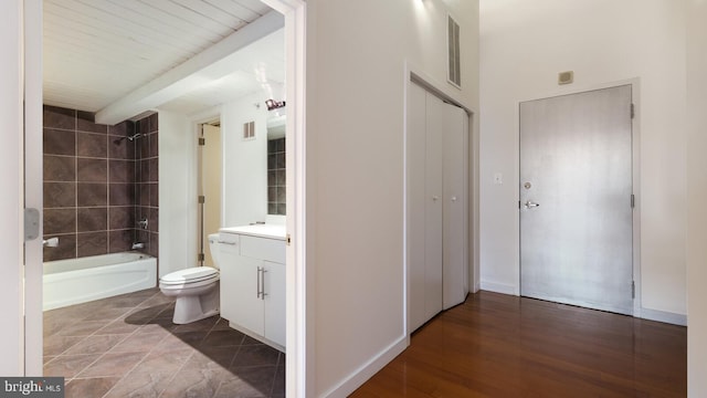 full bathroom with wood-type flooring, vanity, tiled shower / bath combo, and toilet