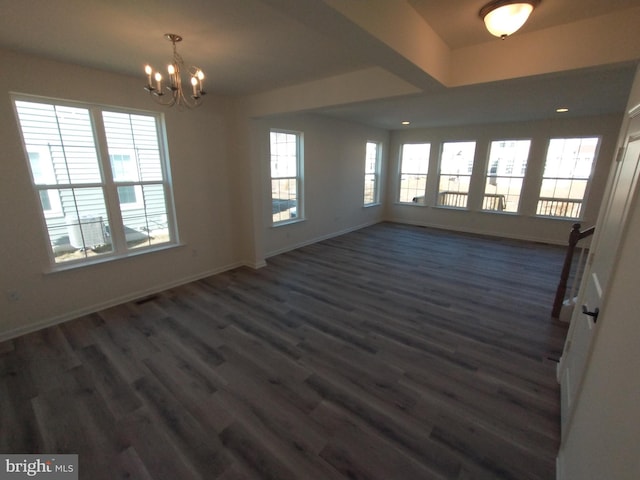 empty room with dark wood-type flooring and an inviting chandelier