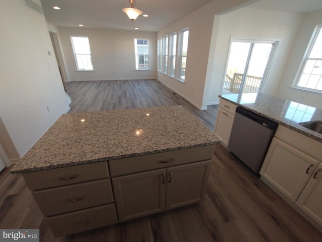 kitchen featuring dark wood-type flooring, white cabinetry, a center island, light stone counters, and stainless steel dishwasher