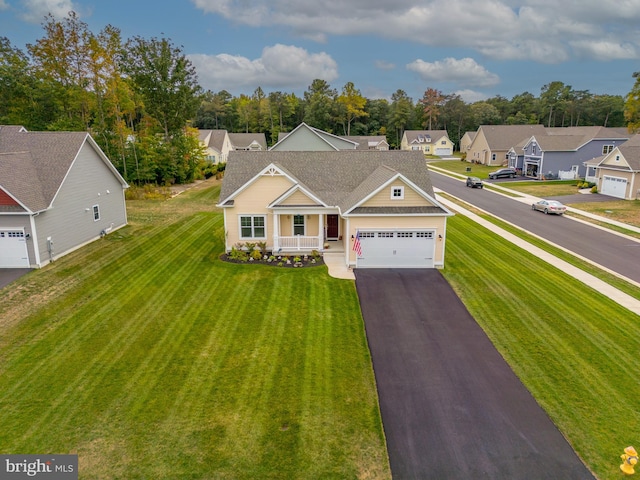 view of front facade featuring a garage, aphalt driveway, a residential view, and a porch