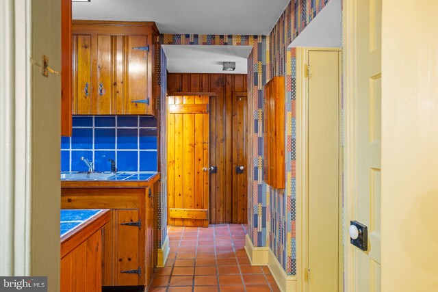 hall featuring wooden walls, sink, and tile patterned floors