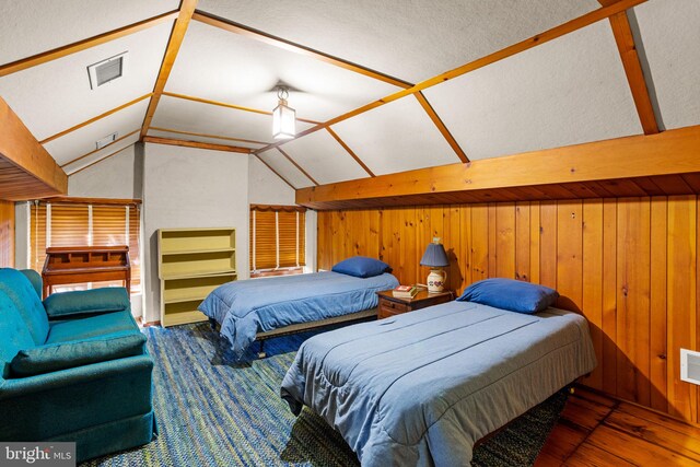 bedroom featuring wooden walls, lofted ceiling, wood-type flooring, and a textured ceiling