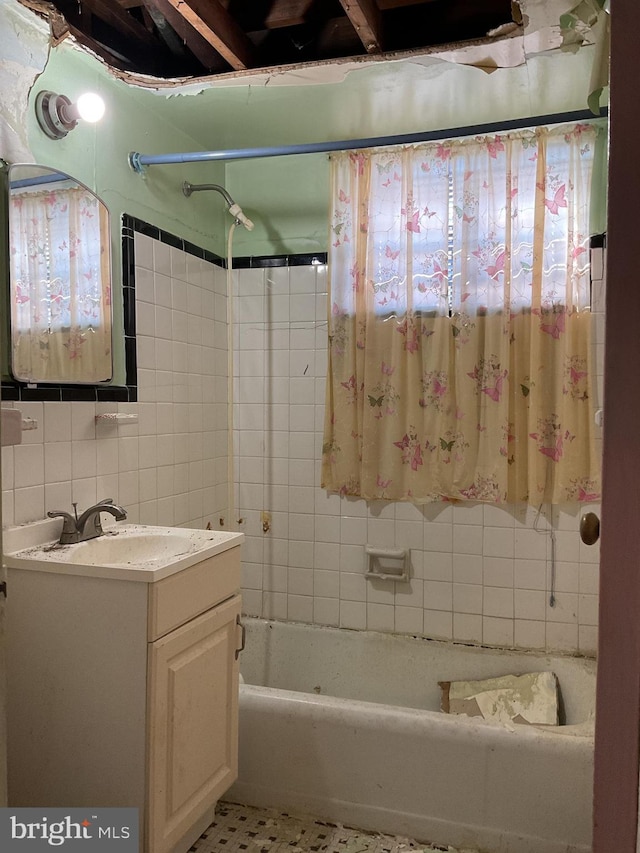 bathroom featuring tile walls, tiled shower / bath combo, vanity, and tasteful backsplash