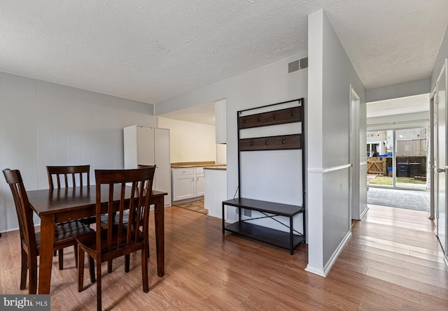 dining area with a textured ceiling and light hardwood / wood-style flooring