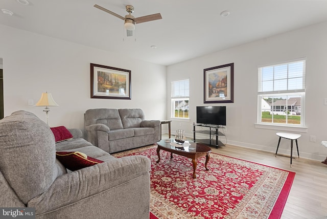 living room with light wood-type flooring, ceiling fan, and a wealth of natural light