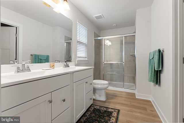 bathroom with a shower with shower door, hardwood / wood-style floors, toilet, and vanity