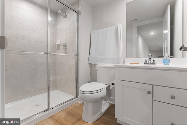 bathroom with a shower with shower door, vanity, wood-type flooring, and toilet