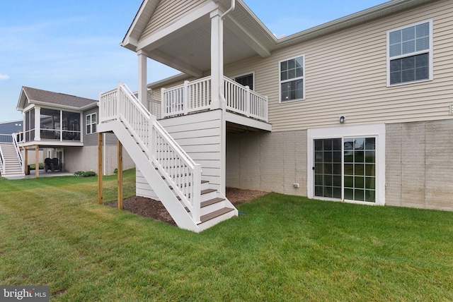 rear view of property featuring a sunroom and a yard