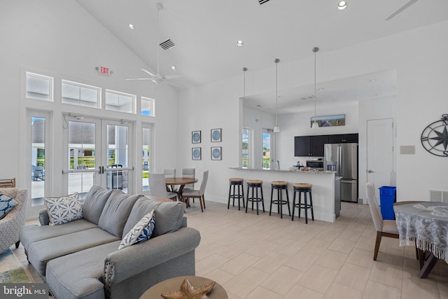 living room featuring ceiling fan, a towering ceiling, and french doors