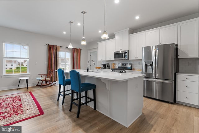 kitchen with appliances with stainless steel finishes, white cabinets, and an island with sink