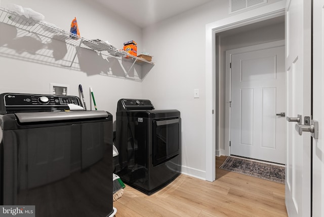 clothes washing area with washing machine and dryer and wood-type flooring