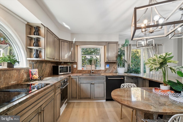 kitchen featuring sink, an inviting chandelier, light wood-type flooring, appliances with stainless steel finishes, and tasteful backsplash