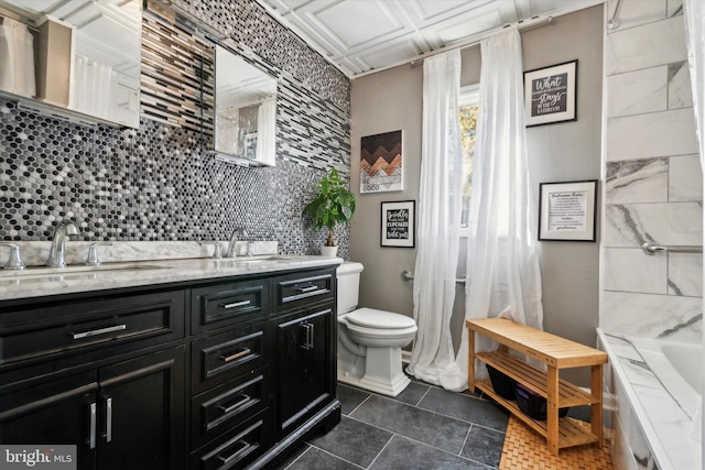 bathroom with a tub, backsplash, toilet, vanity, and tile patterned floors