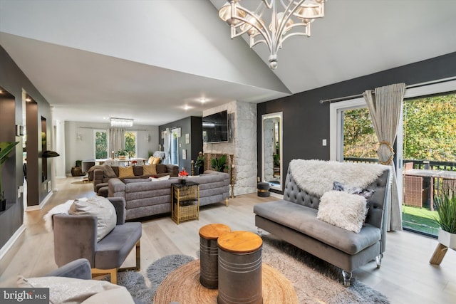 living room featuring light hardwood / wood-style floors, an inviting chandelier, vaulted ceiling, and a wealth of natural light