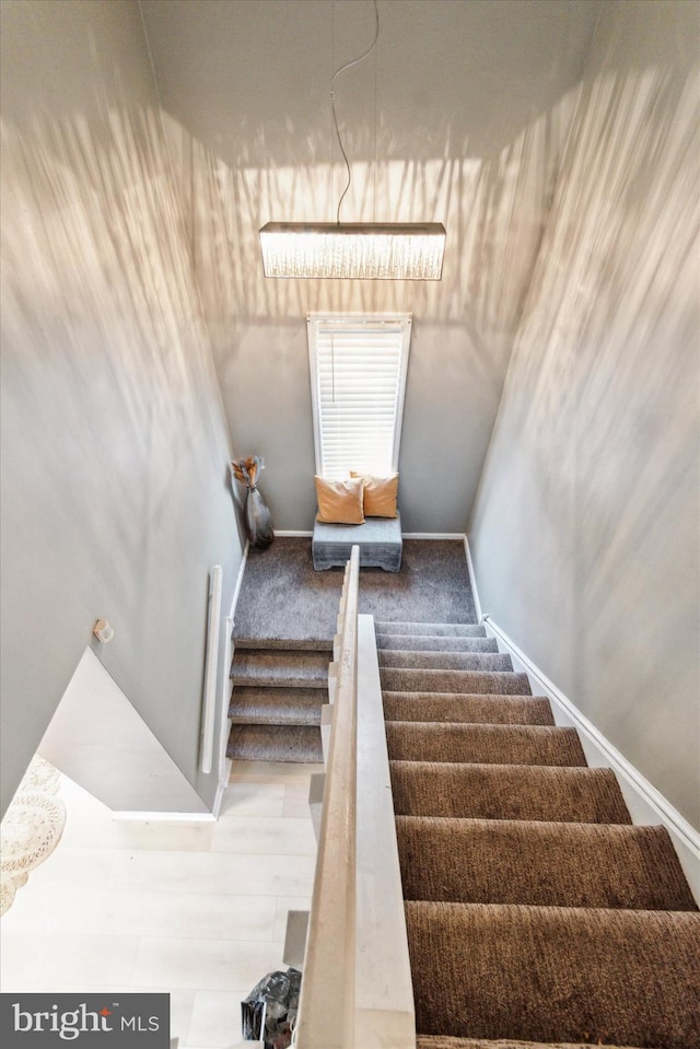 staircase with a chandelier and hardwood / wood-style flooring