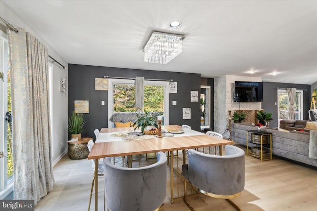 dining room with light hardwood / wood-style flooring, a notable chandelier, and a large fireplace