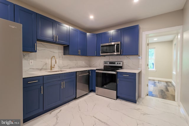 kitchen with appliances with stainless steel finishes, blue cabinets, sink, and tasteful backsplash