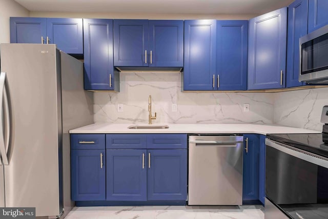 kitchen with appliances with stainless steel finishes, tasteful backsplash, blue cabinetry, and sink