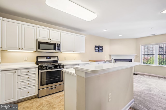 kitchen with appliances with stainless steel finishes, light carpet, a center island with sink, and white cabinets