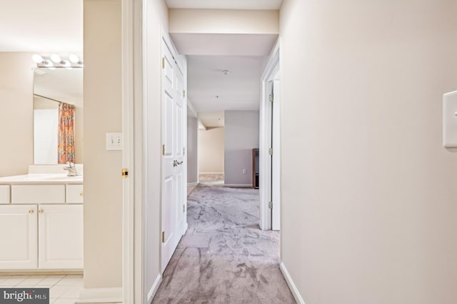 hallway featuring sink and light colored carpet